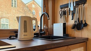 Eine Küche mit einer PHILIPS-Kaffeemaschine, einem schwarzen Wasserhahn und einem Messerbrett mit verschiedenen Küchenutensilien.