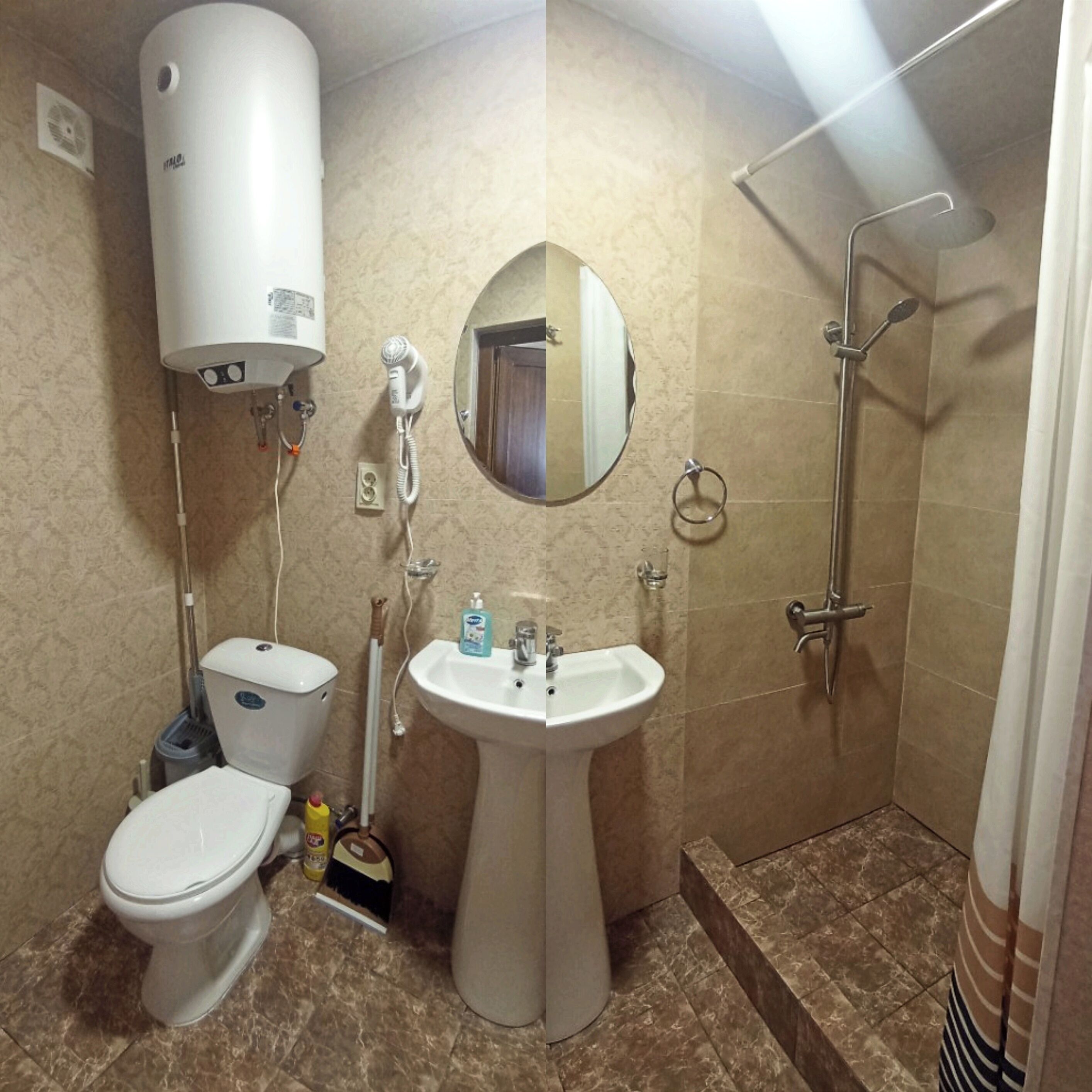 A bathroom with a toilet, sink, mirror, shower, and a water heater.