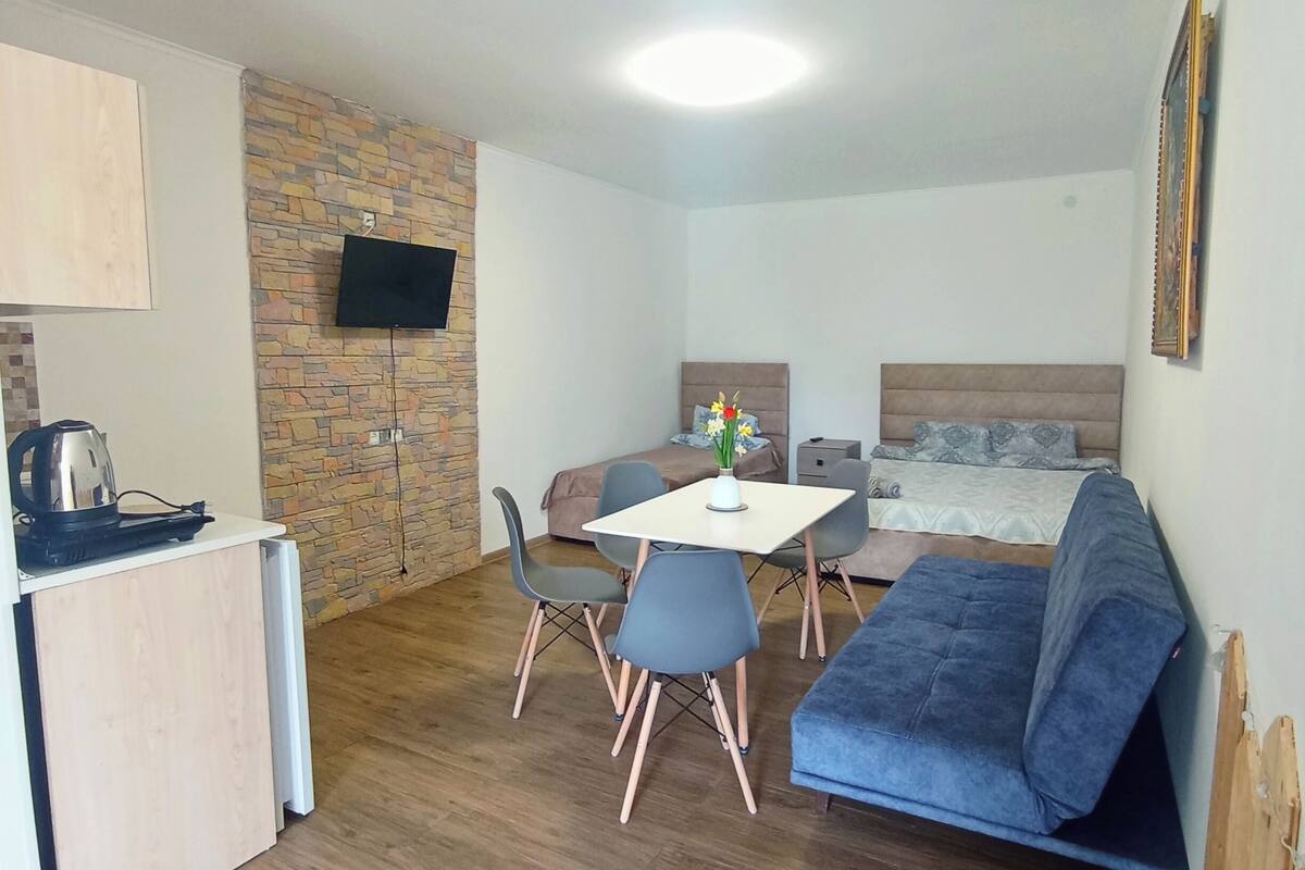 A compact room with a kitchenette, a dining area, and a bed.