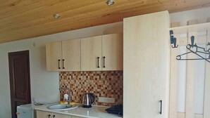 A compact kitchen with wooden cabinets, a sink, and a kettle. - Amrakits Canyon Guesthouse (Amrakits)