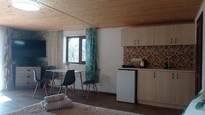 A compact living space with a dining area, kitchenette, and a TV mounted on the wall. - Amrakits Canyon Guesthouse (Amrakits)