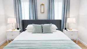 Una camera da letto ordinata con un letto grande, due comodini con lampade e uno specchio a parete.
