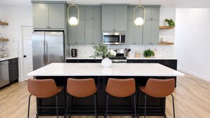 Una cucina moderna con un'isola grande, elettrodomestici in acciaio inossidabile e illuminazione a sospensione.