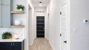 Una cucina moderna con mobili scuri, un piano di lavoro bianco e un pavimento in legno.