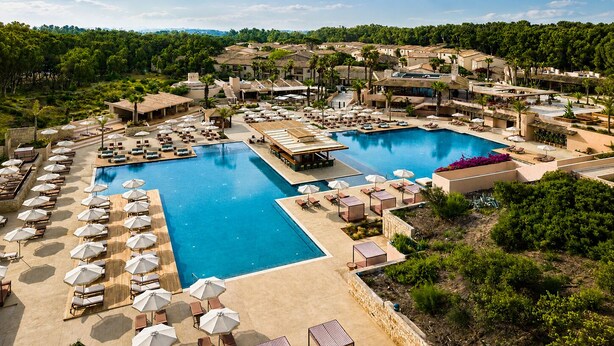 Un complexe hôtelier doté de plusieurs piscines, d’espaces de détente et offrant une vue sur un paysage montagneux.