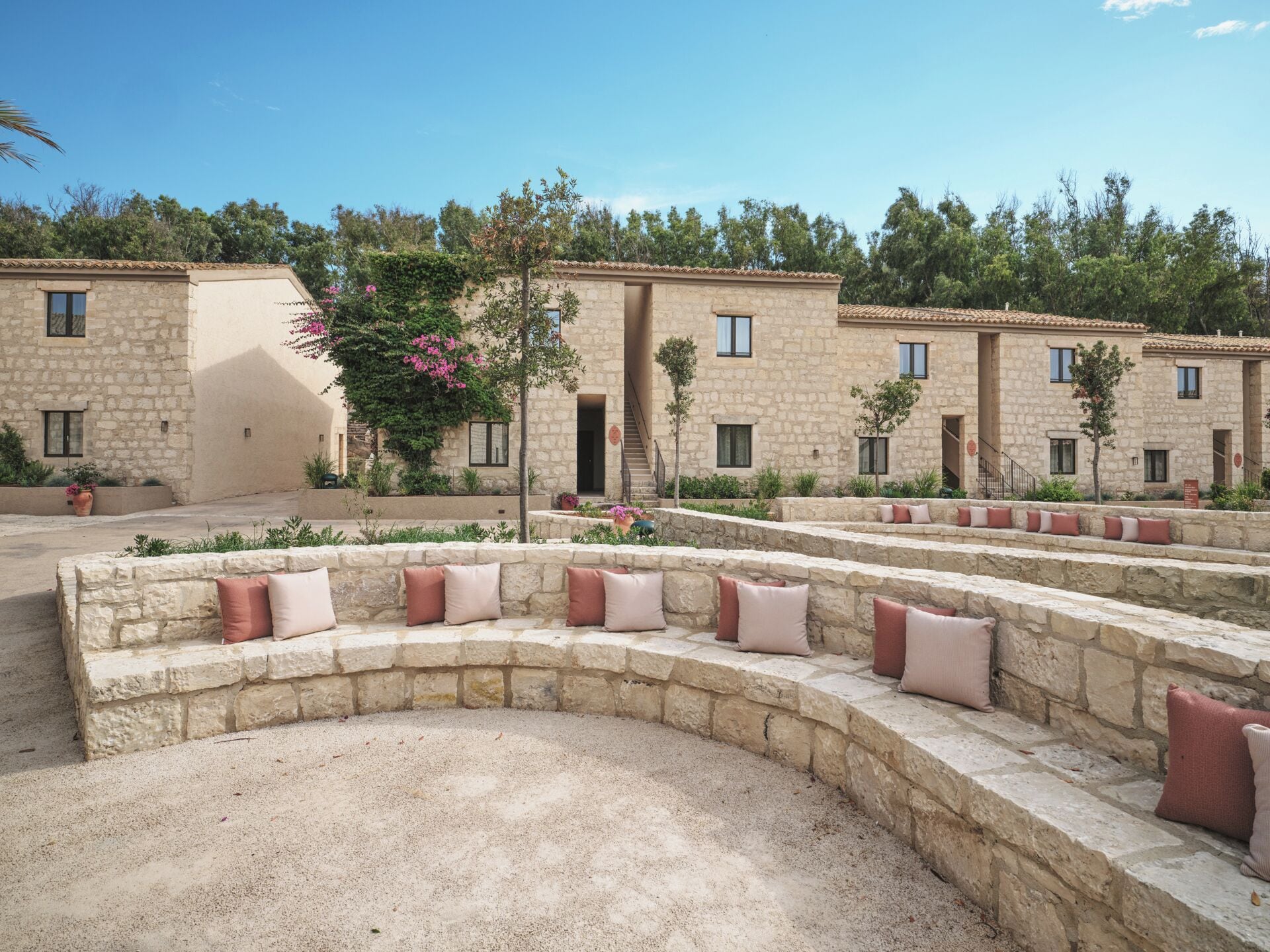 Un patio con bancos de piedra y un muro de piedra.