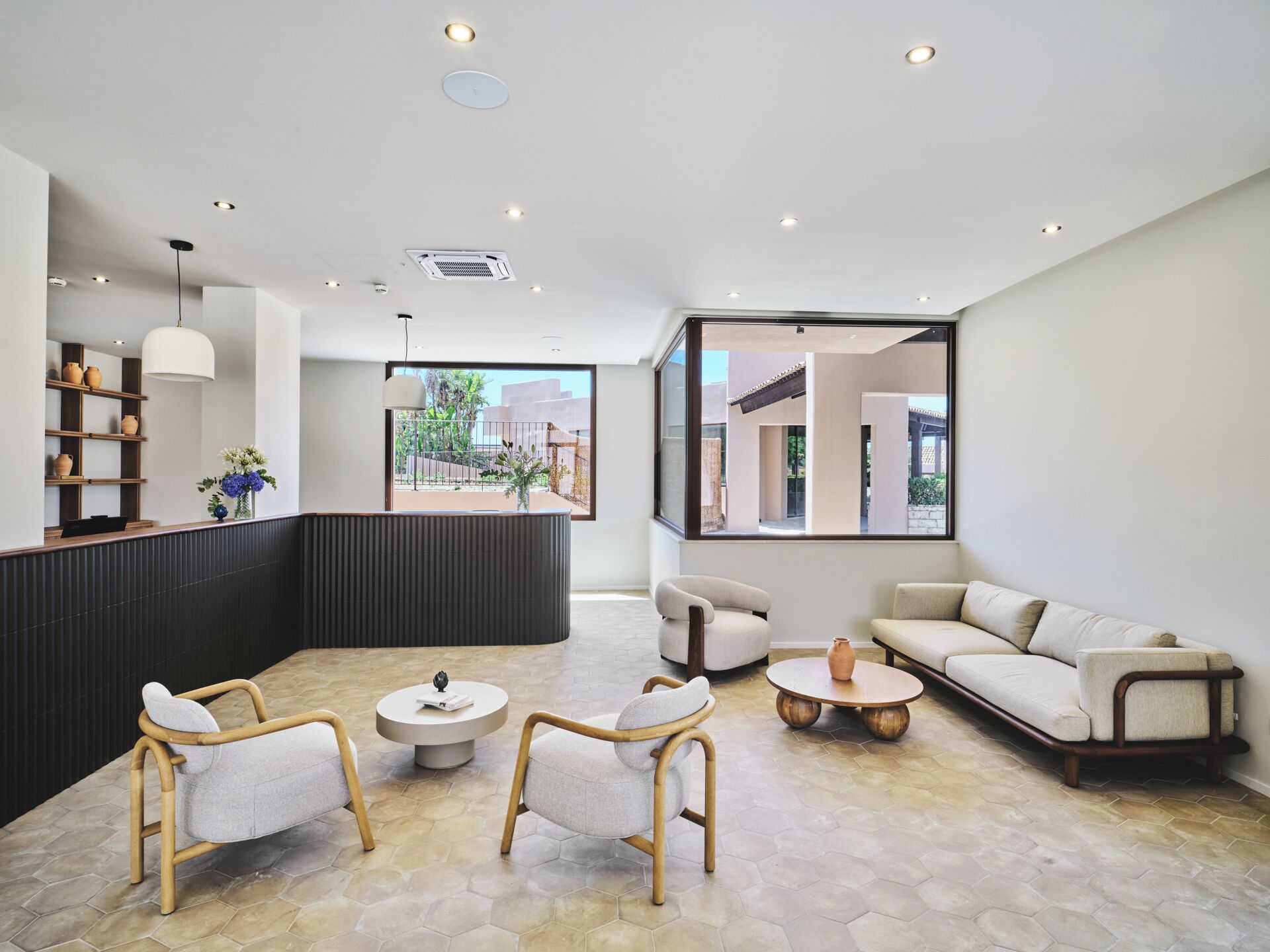 A modern interior with a seating area, a reception desk, and a large window offering a view of the outside.