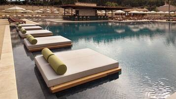 A pool with lounge chairs and umbrellas.