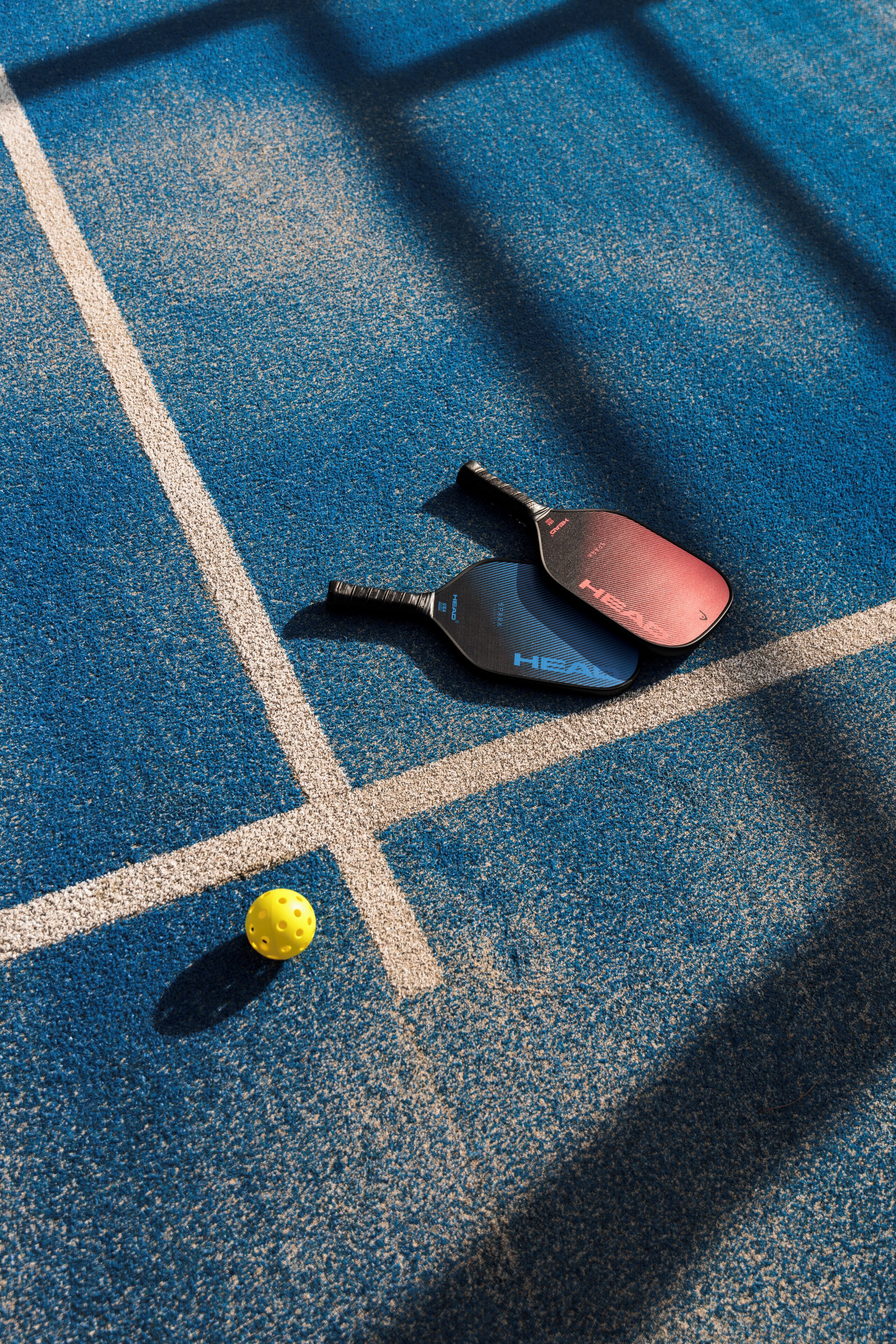 A tennis court with a net, a tennis racket, and a tennis ball.