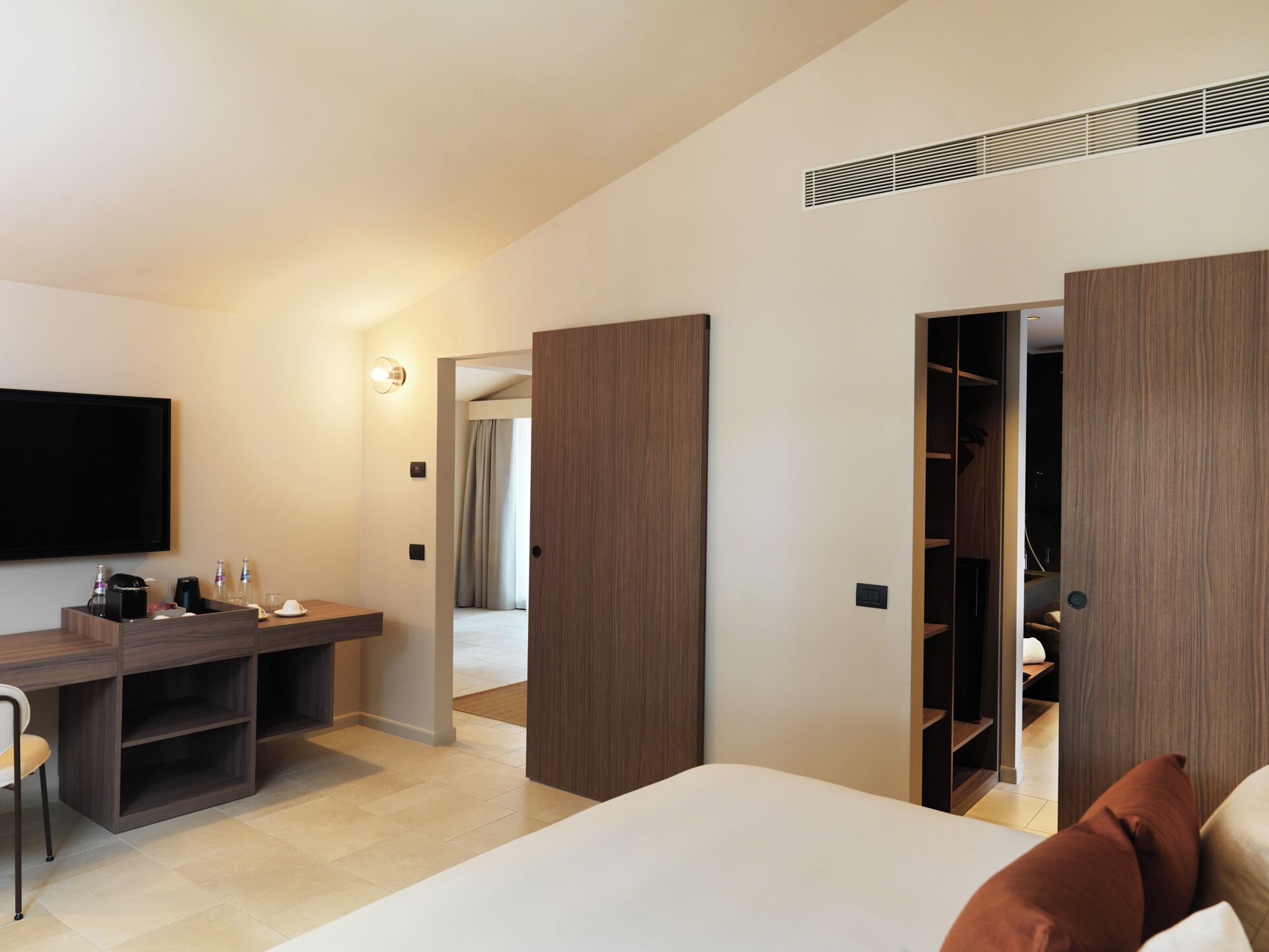 Ein modernes Hotelzimmer mit einem Bett, einem Schreibtisch, einem Fernseher und einem Kleiderschrank.