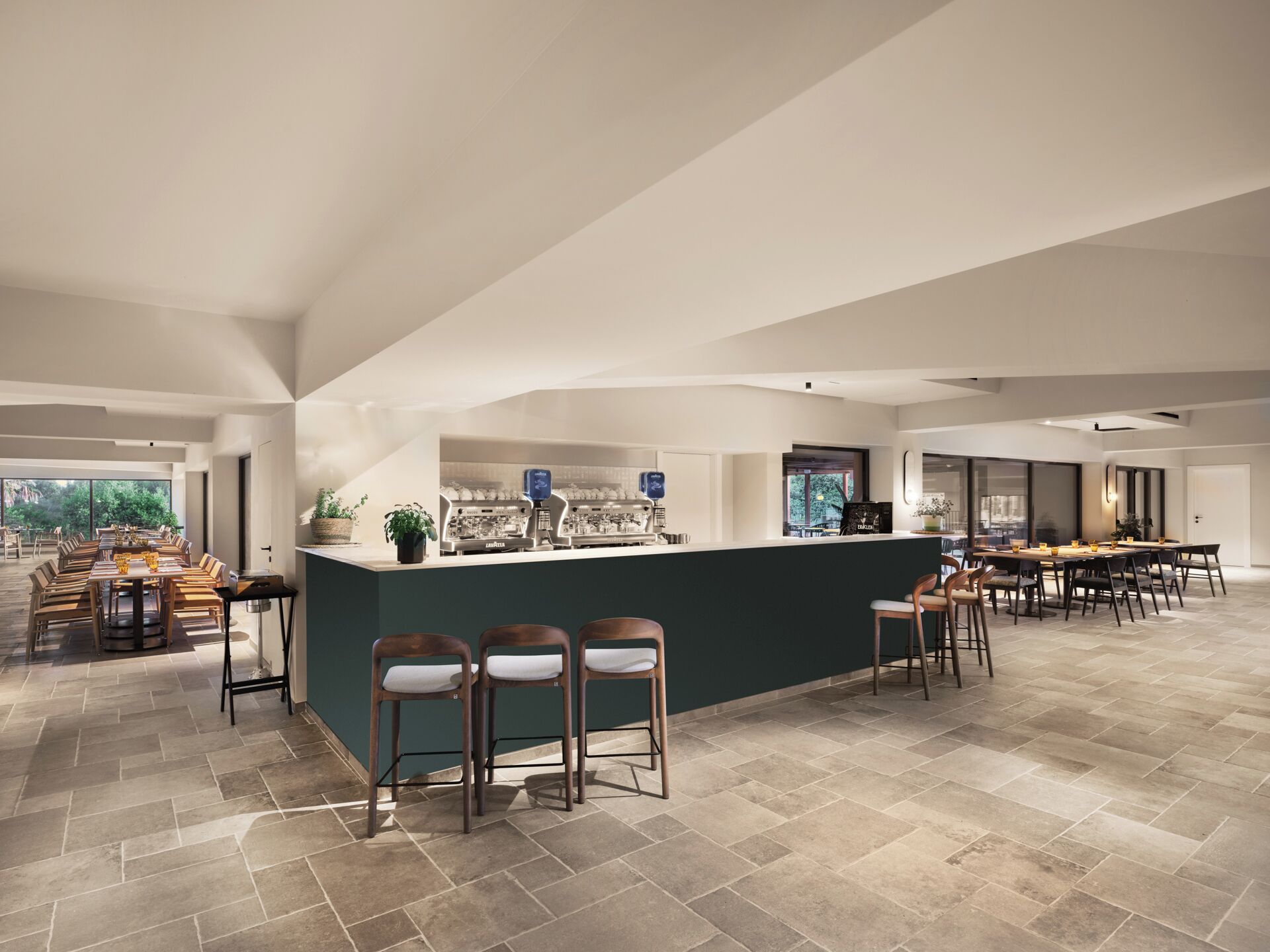 A spacious bar area with a long counter, multiple seating options, and a view of the outdoors.