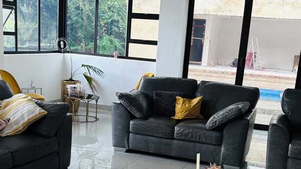 A modern living room with a black sofa, a yellow bean bag, and a coffee table.