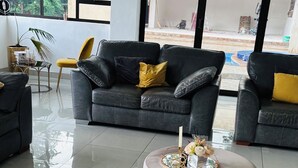 A modern living room with a black leather sofa, a yellow bean bag, and a round coffee table with a decorative centerpiece.