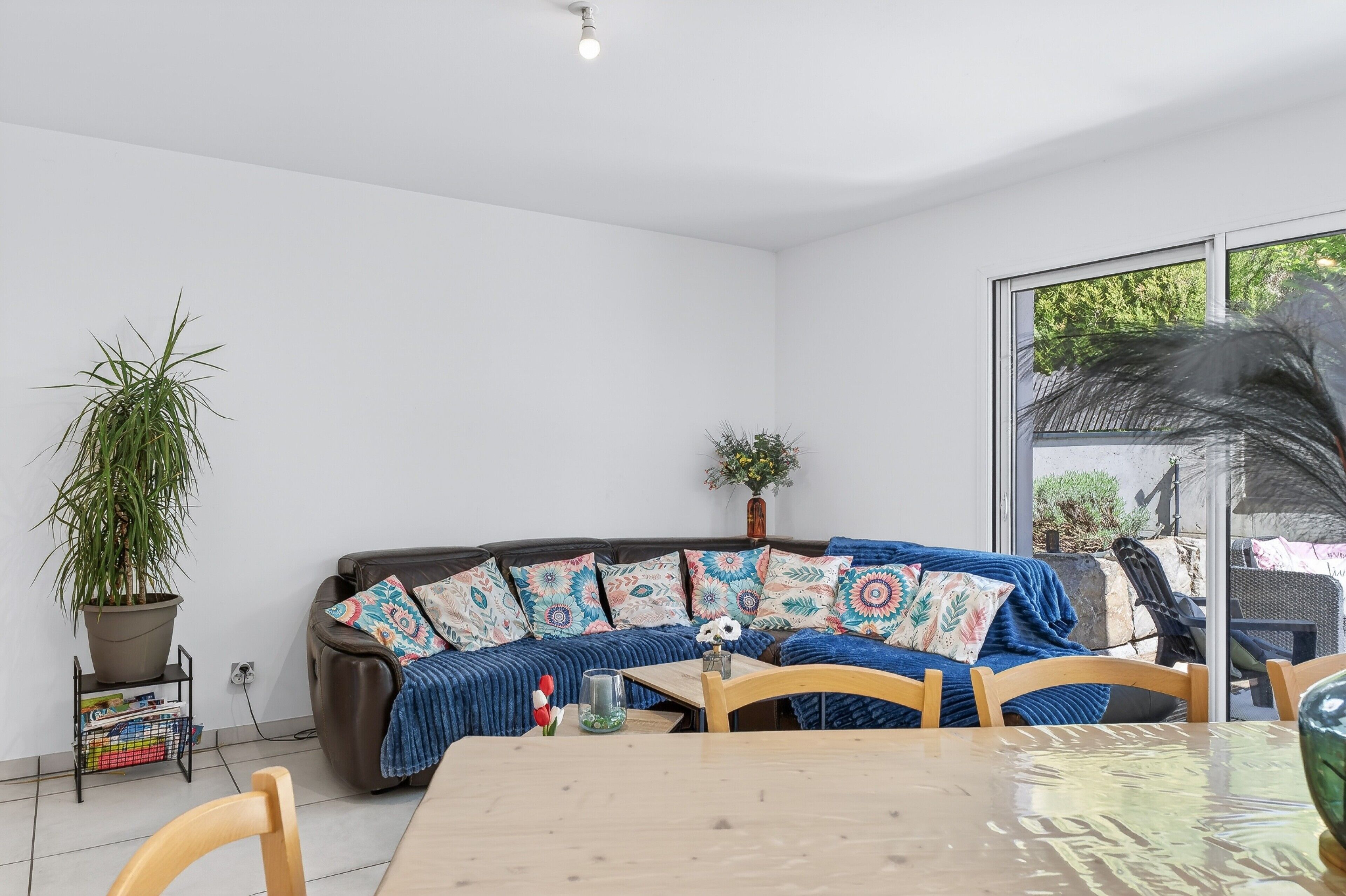 Una sala moderna con un sofá modular, una mesa de comedor y una planta en maceta.