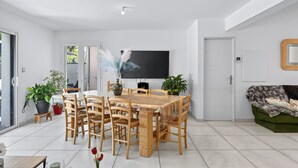 Un comedor moderno con una mesa y sillas de madera, un televisor de pantalla plana y plantas en macetas.