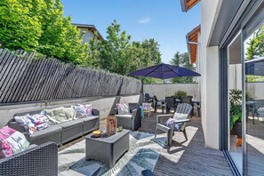 An outdoor patio with a sofa, chairs, a table, and an umbrella. - Holiday Home in the Heart of Chorges Village (Chorges)