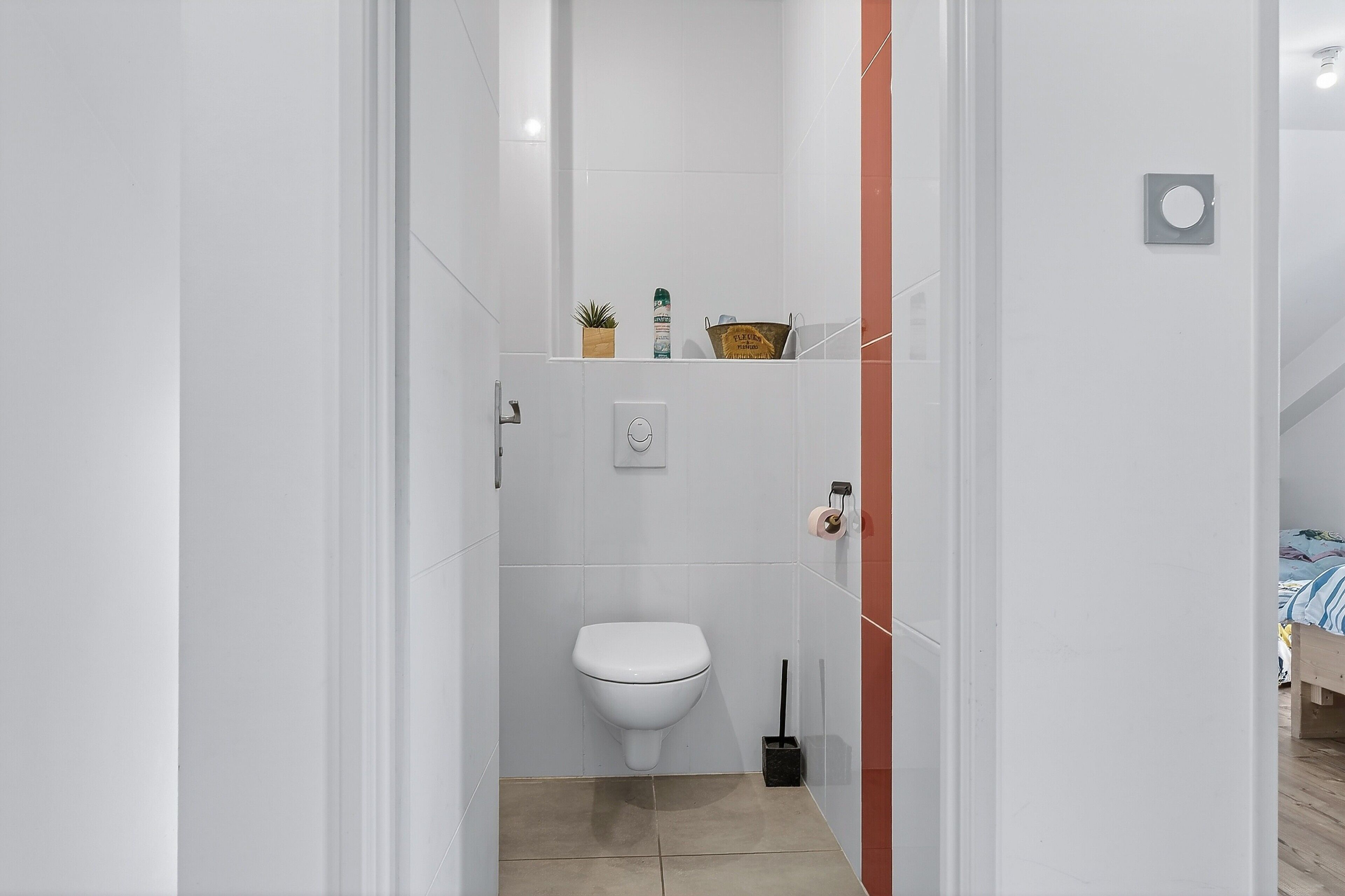Ein Badezimmer mit Toilette, einer kleinen Ablage für Toilettenartikel und einer Duschkabine.