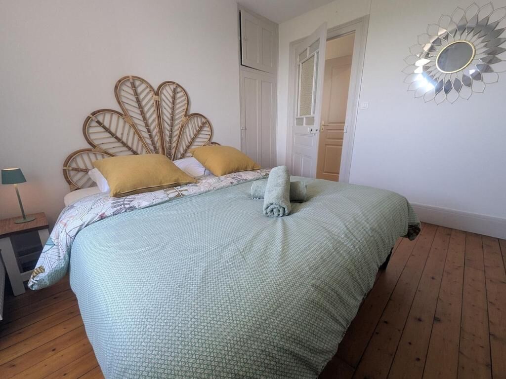 Een slaapkamer met een bed, nachtkastje, spiegel en deur.