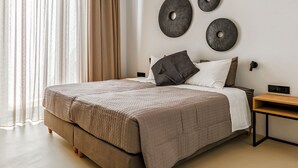 A modern bedroom with a large bed, a bedside table, and wall-mounted decor. - Paros Villa Skylines Estate I (Paros)
