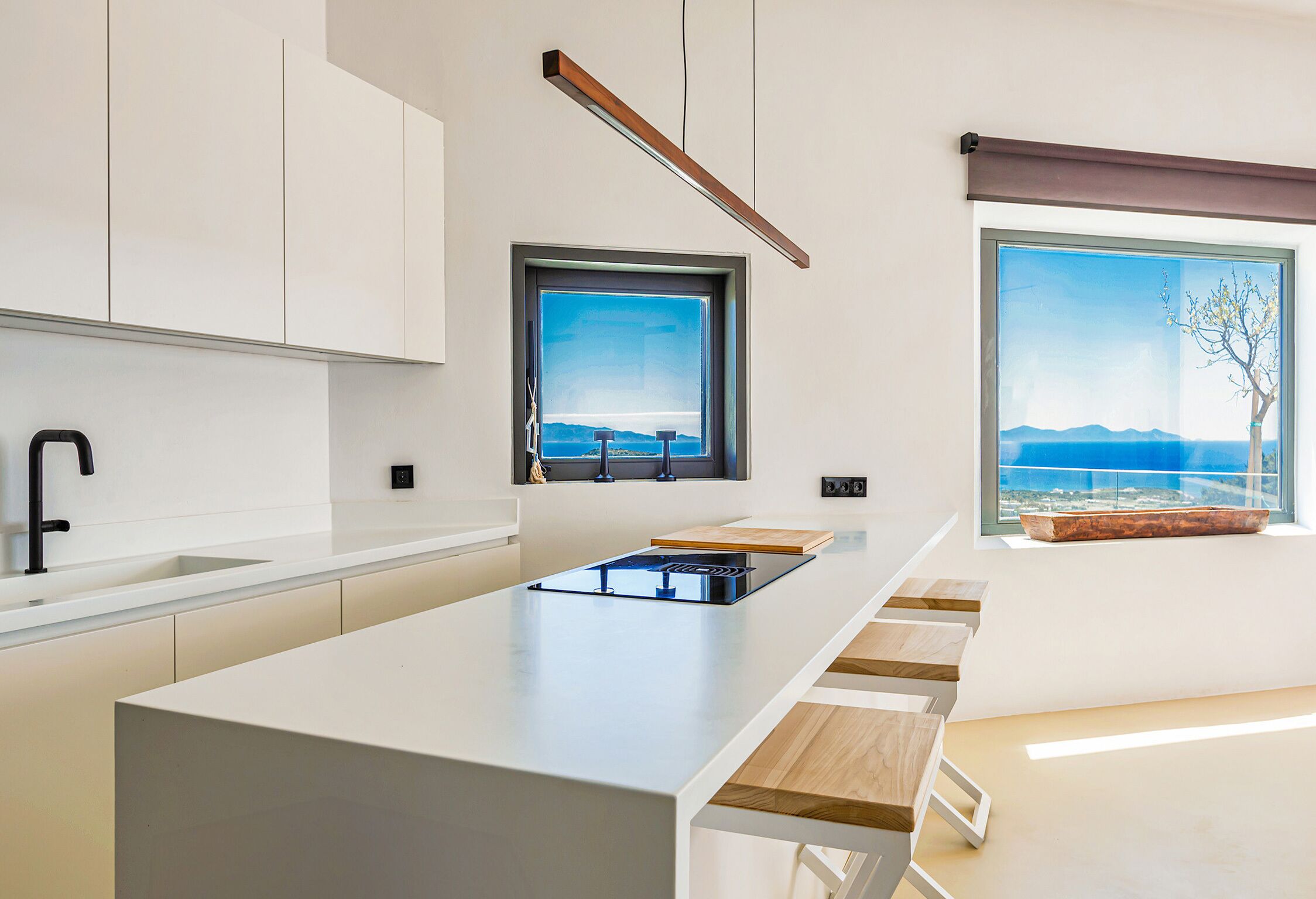 Eine moderne Küche mit einer zentralen Kochinsel, einem Fenster mit Ausblick und eingebauten Schränken.