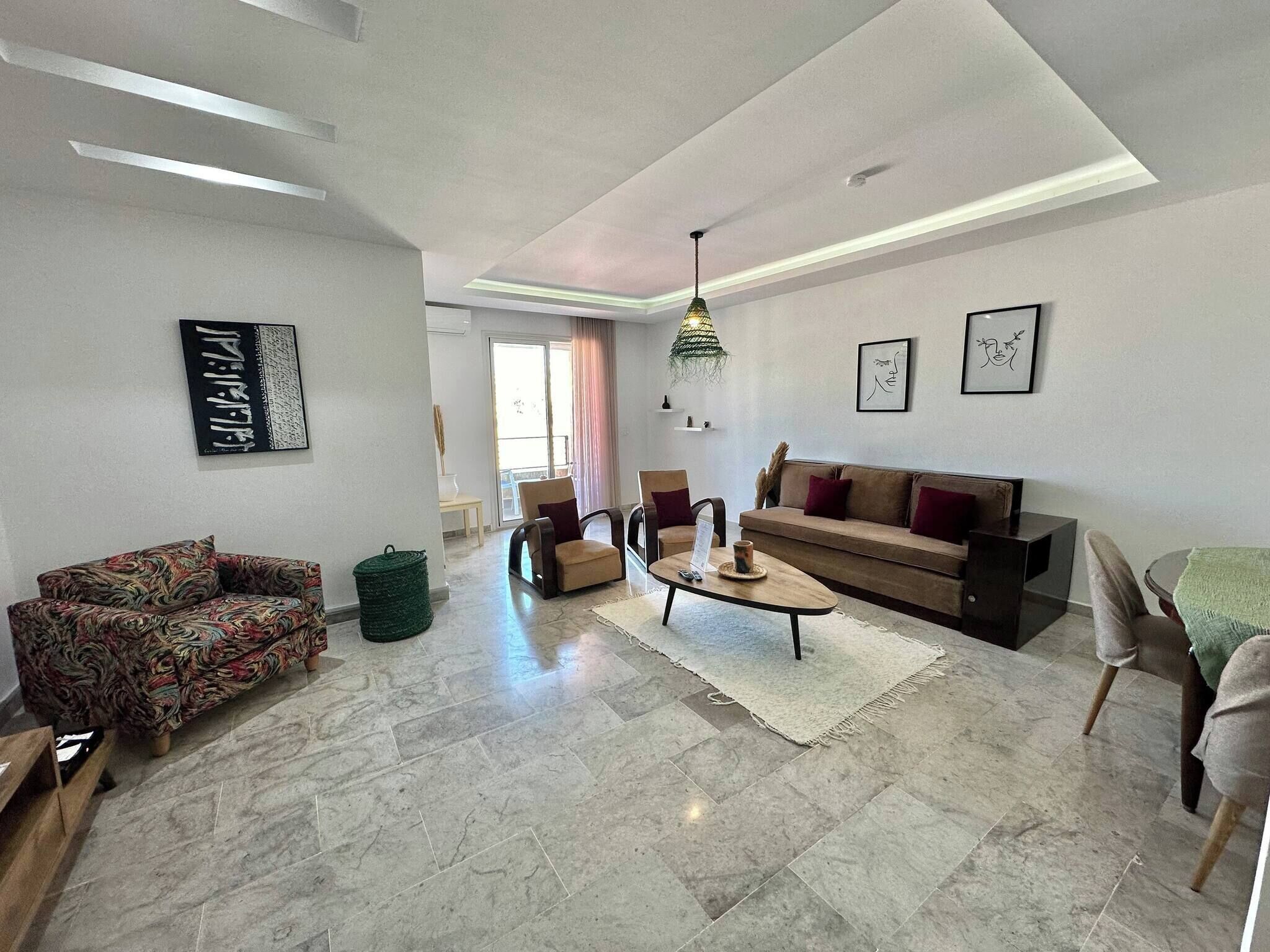 Un salón amplio con sofá, sillas, una mesa de centro y un ventanal grande.