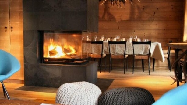 Ein gemütliches Zimmer mit Kamin, Holzwänden und einem Essbereich mit Stühlen und Tisch.