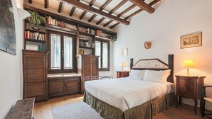 A bedroom with a large bed, wooden furniture, a bookshelf, and a window with curtains. - Apartments Florence - Nido Fiorentino (Florence)