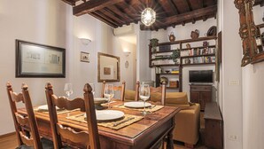 A dining area with a wooden table set for four, surrounded by chairs. - Apartments Florence - Nido Fiorentino (Florence)