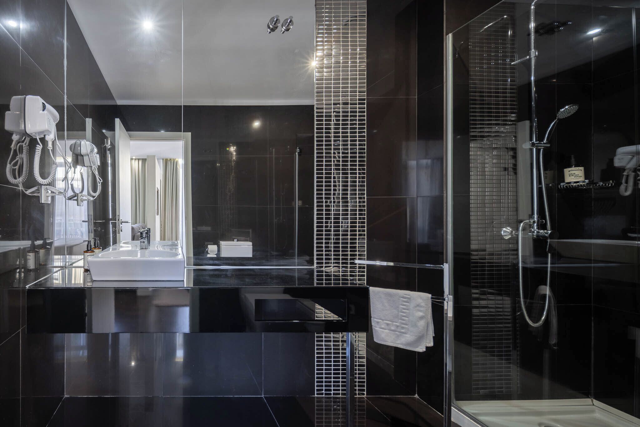 A modern bathroom with a glass-enclosed shower, a white sink, and a mirror.