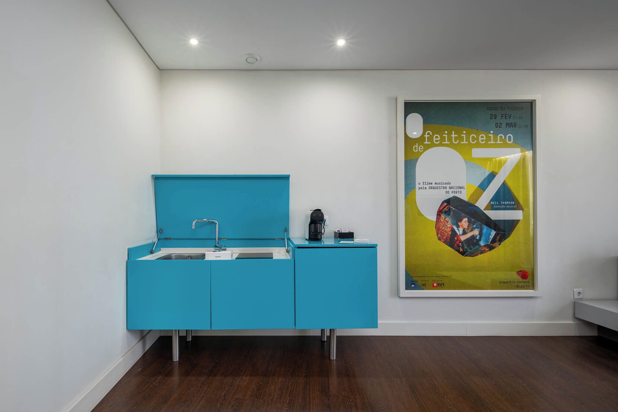 A modern kitchen with a blue countertop and a poster on the wall.
