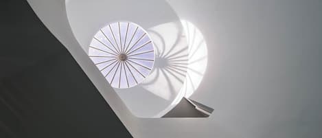 A modern architectural design with a circular skylight and a spiral staircase.