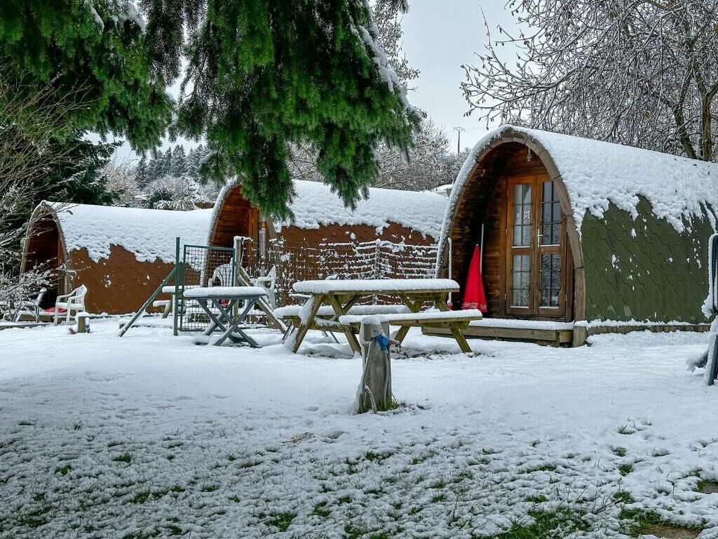 Una cabaña rústica con techo nevado y puerta de madera.