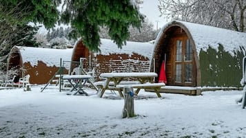 Una cabaña rústica con techo nevado y puerta de madera.