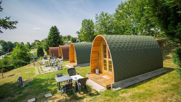 Una fila di cabine a forma di cupola con terrazze in legno e zone relax all'aperto.