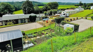 Una proprietà rurale con un ampio giardino, un'area giochi recintata e un piccolo edificio con tetto in metallo.