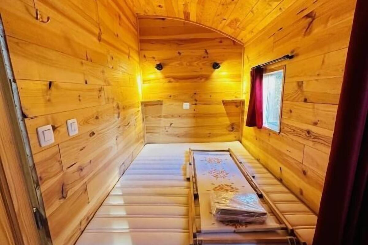 Ein kleines, gemütliches Blockhauszimmer mit Holzwänden und einem Einzelbett.