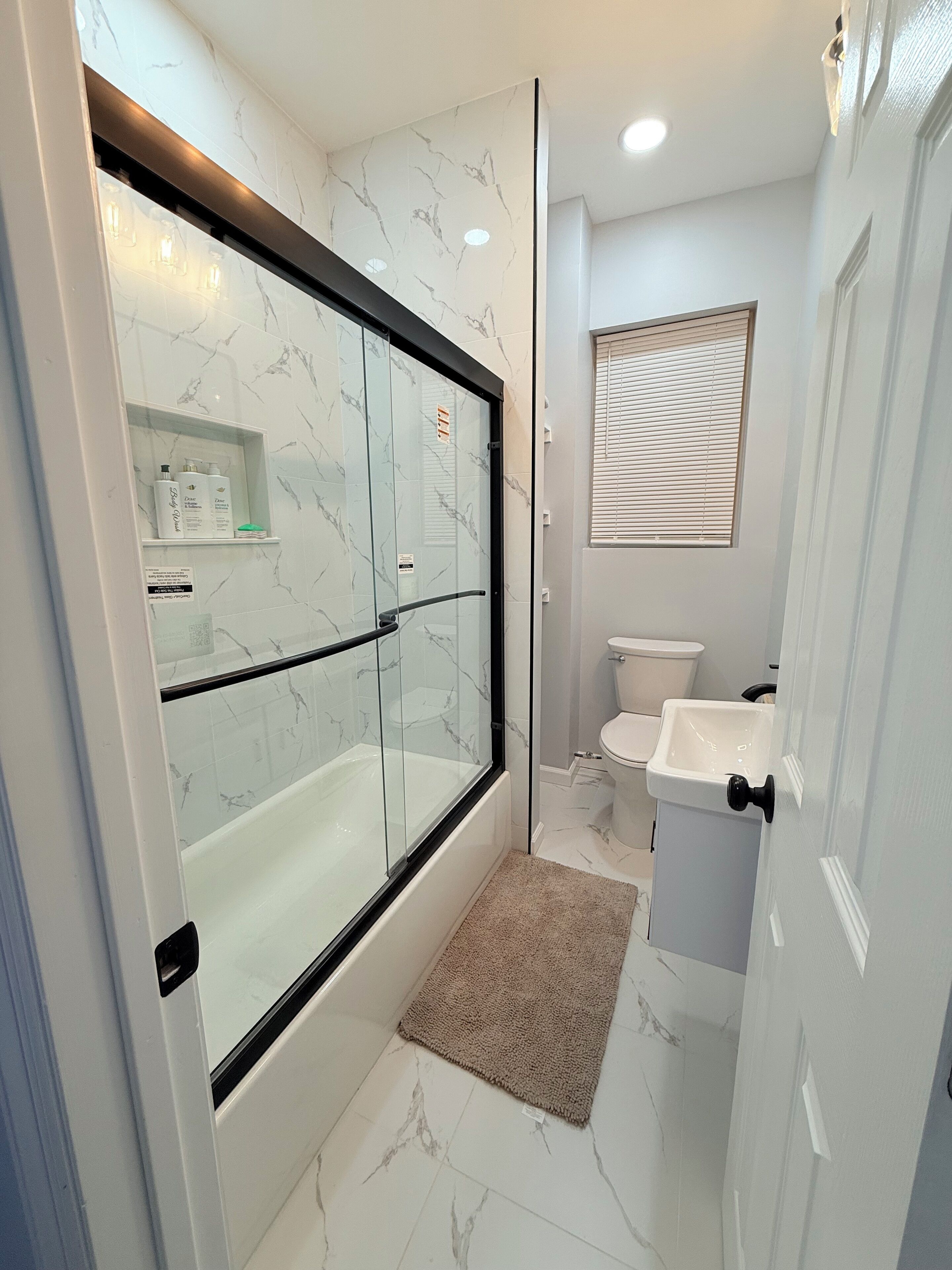 A modern bathroom with a glass-enclosed shower, a toilet, and a sink.