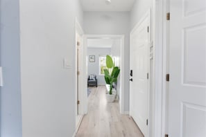 Un pasillo con paredes blancas, suelo de madera y una planta en maceta.