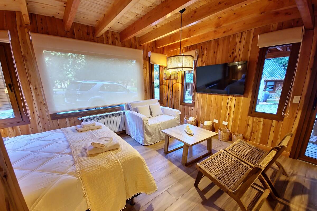 Een gezellig houten kamer met een bed, een bank, een tafel en een televisie.