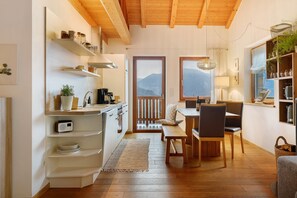 A compact kitchen with wooden shelves, a dining area with a bench, and a view of mountains through a door. - Apartment 'Lisahitl' with Shared Pool, Private Terrace and Wi-Fi (Renon)