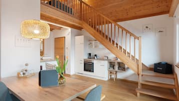 A modern kitchen with white cabinets, a wooden staircase, and a dining area with a table and chairs.