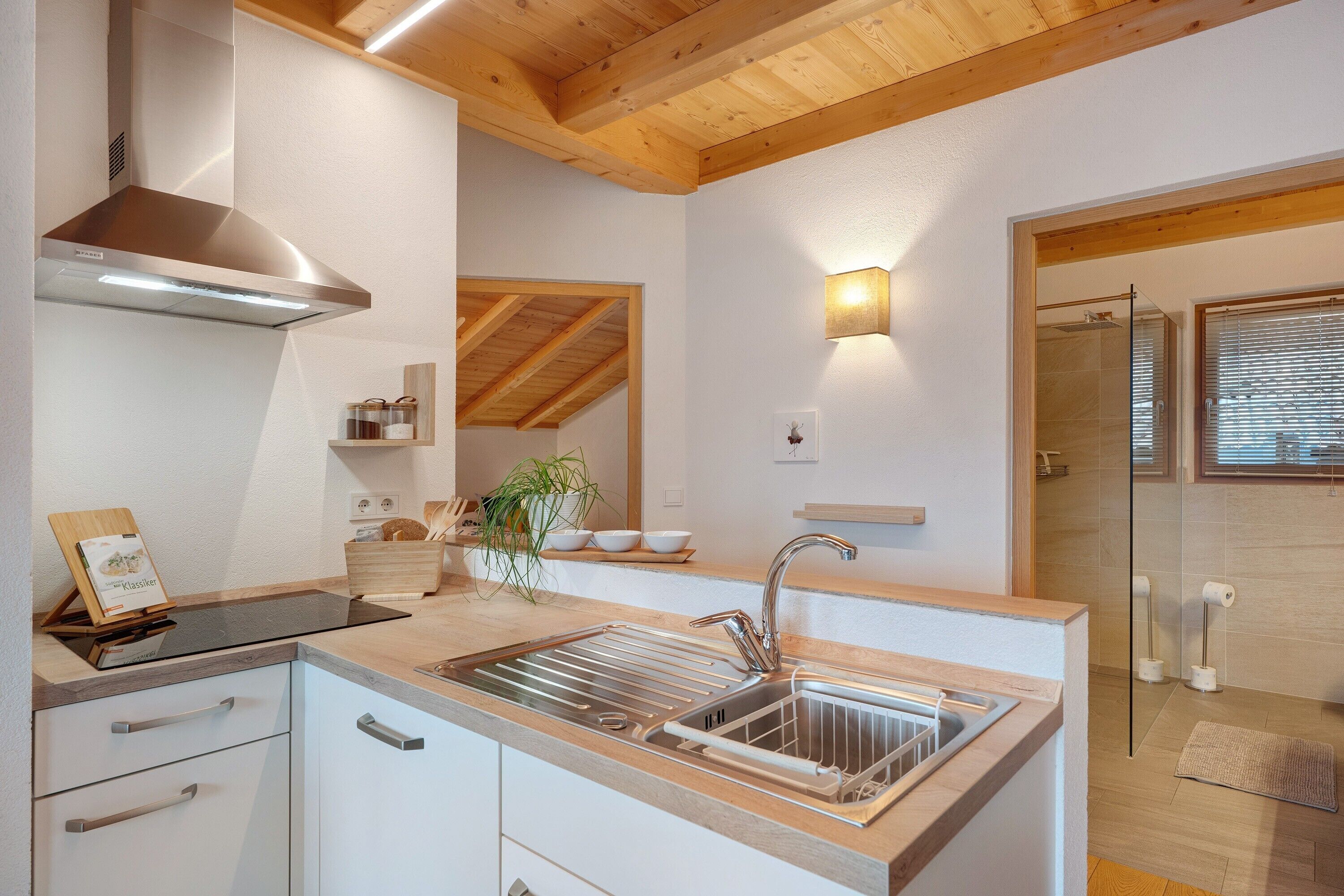 A modern kitchen with a stainless steel sink, wooden countertop, and a built-in stove.