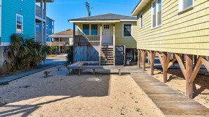 A beachfront property with a wooden deck, a covered porch, and a sandy beach area. - AJ: 3 Bedroom Oceanfront Duplex (Carolina Beach)