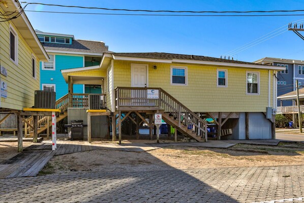 Una casa de dos pisos con una terraza de madera y una escalera que lleva al segundo piso.