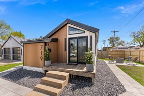 A modern house with a wooden exterior, a large sliding glass door, and a small porch with steps.