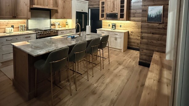Een landelijke keuken met houten wanden, een groot eiland met barstoelen en moderne apparaten.
