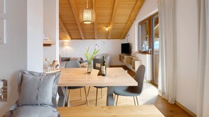 Un interior moderno con una mesa de comedor de madera, sillas, un sofá y un televisor.