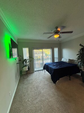 A bedroom with a bed, ceiling fan, and a view through the window. - Cozy 1-bedroom apartment in Galleria Houston with pool and gym access (Houston)