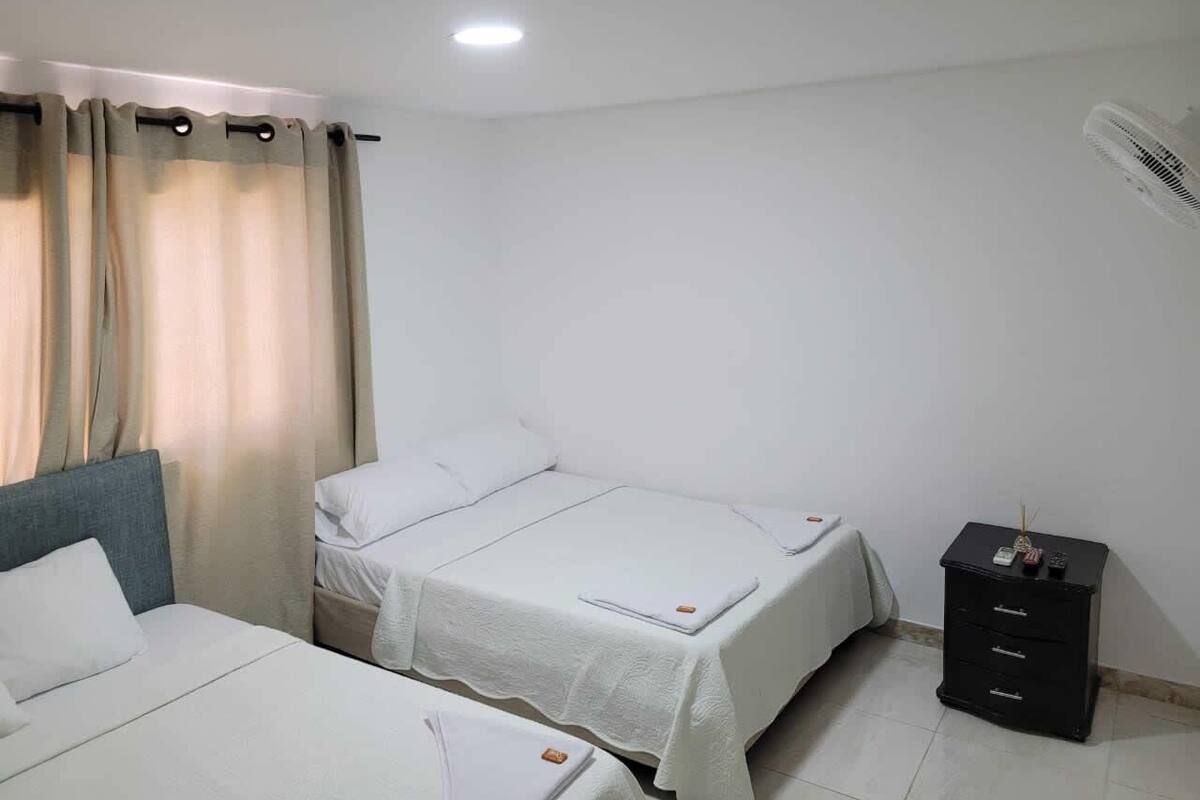 A hotel room with two beds, a nightstand, and a ceiling fan.