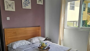 A bedroom with a wooden bed, a gray bedspread, and a basket of toiletries on the bed. - House of the Three Companions (Gros Islet)